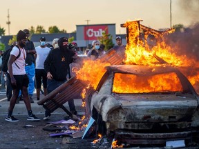 Protesters throw objects onto a burning car outside a Target store on May 28, 2020 in Minneapolis.