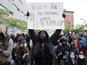 A protester holds up a sign during a demonstration calling for justice in the death of George Floyd and victims of police brutality in Montreal, Sunday, May 31, 2020./