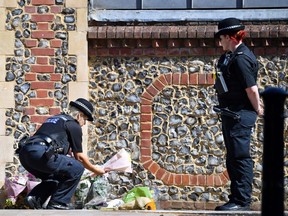 A police officers lays flowers, given by a member of the public, at an entrance of Forbury Gardens park in Reading, west of London, on June 22, 2020.