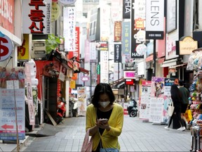 A woman wearing a mask looks at her mobile phone amid social distancing measures in Myeongdong shopping district in Seoul, South Korea, May 28, 2020.