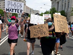 Demonstrators hold placards as they march to the White House during a peaceful protest against police brutality and racism, on June 6, 2020 in Washington.