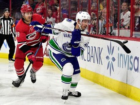 Sven Baertschi of the Vancouver Canucks moves the puck as Dougie Hamilton of the Carolina Hurricanes defends at PNC Arena on October 9, 2018 in Raleigh, North Carolina.