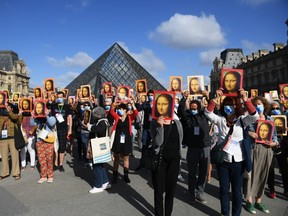 Visitors hold reproductions of the Mona Lisa outside the Louvre museum as it reopens its doors following its 16 week closure due to lockdown measures caused by the COVID-19 coronavirus pandemic, at the Louvre on July 6, 2020 in Paris.