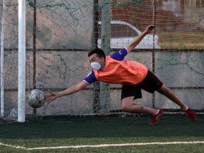 A man wearing a face mask makes a save during a football match at a local club prepared as a human foosball pitch with zones for each player to avoid physical contact, during the spread of the coronavirus disease (COVID-19), in Pergamino, Argentina July 4, 2020.