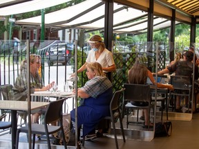 Patrons are separated by plexiglass sheets as they return to restaurants on the first day after novel coronavirus restrictions were lifted to visit restaurants in Montreal, June 22, 2020.