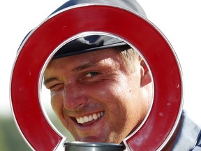 Bryson DeChambeau looks through the trophy after winning the Rocket Mortgage Classic at Detroit Golf Club yesterday.