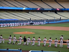 Players from the Los Angeles Dodgers and the San Francisco Giants take a knee during the national anthem at Dodger Stadium.