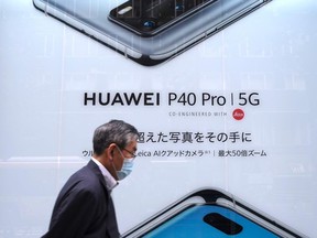 In this picture taken on June 27, 2020, a man walks past an advertisement for the latest smartphone by Chinese telecommunications company Huawei in Tokyo.