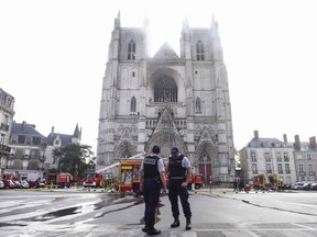 French Police officers stand ready as firefighters are at work to put out a fire at the Saint-Pierre-et-Saint-Paul cathedral in Nantes, western France, on July 18, 2020.