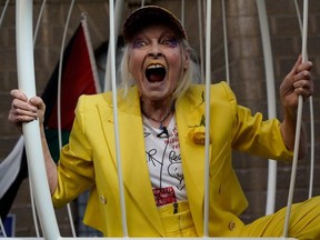 British designer Vivienne Westwood gestures from inside a ginat bird-cage, suspeneded off the ground, in front Of the Old Bailey in central London on July 21, 2020, in protest of the extradition trial of Wikileaks founder Julian Assange.
