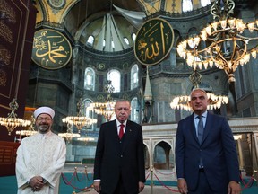 This handout picture released by the Turkish presidential press office on July 23,2020, shows Turkey's President Recep  Tayyip Erdogan (C), Tourism Minister Mehmet Nuri Ersoy (R) and Head of Turkey's Religious Affairs Directorate Ali Erbas (L) pose  posing the Hagia Sophia mosque in Istanbul.