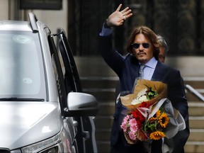 U.S. actor Johnny Depp gestures holding a bunch of flowers as he leaves after a hearing in his libel trial against News Group Newspapers (NGN), at the High Court in London, on July 24, 2020.