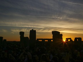 In this file photo revellers watch the sunrise as they celebrate the pagan festival of Summer Solstice at Stonehenge in Wiltshire, southern England on June 21, 2018.