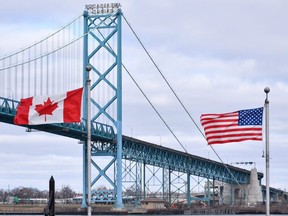 Canadian and American flags fly near the Ambassador Bridge at the Canada-USA border crossing in Windsor, Ont. on Saturday, March 21, 2020.