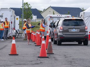 Volunteers examine the documents of motorists who just came off the Confederation Bridge in Borden-Carleton, P.E.I., Friday, July 3, 2020.