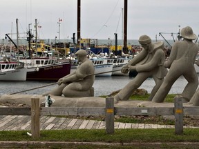 A sculpture shows fishermen pulling on a line in front of the marina, Monday, August 6, 2012 in L'Étang du Nord on the Magdalen Islands. Quebecers traveling to the Iles-de-la-Madeleine this summer will not be able to stop in New Brunswick overnight, after restrictions on inter-provincial travel were tightened this week.