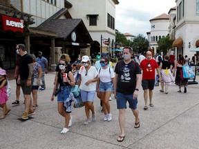 Disney Springs shoppers wear face masks and Disney-themed clothing while Walt Disney World conducts a phased reopening from COVID-19 restrictions in Lake Buena Vista, Fla., July 11, 2020.