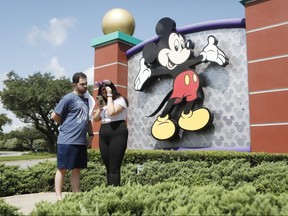 Michael Callahan and Sarah Breland look over photos taken near the Walt Disney World park entrance on July 9, 2020 in Lake Buena Vista, Florida.