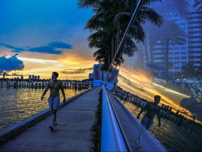 A man walks as the  sun sets in the background in Miami Beach on July 14, 2020, amid the coronavirus pandemic.