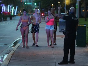 A police officer directs people out of the entertainment district as a curfew is put in place on July 18, 2020 in Miami Beach, Florida.