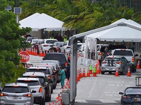 Cars line up for COVID-19 tests at a "walk-in" and "drive-through" coronavirus testing site in Miami Beach, Fla., July 22, 2020.