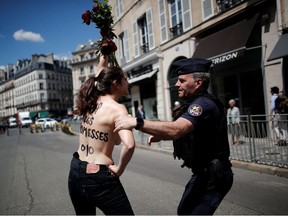 French police apprehend a topless woman who protests in front the Elysee Palace before the first weekly cabinet meeting of the new French government in Paris, France, July 7, 2020. The slogan reads " RIP the pledges".