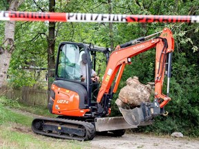 An excavator removes stone as police officers search a garden in the northern German city of Hanover on Tuesday, July 28, 2020, in connection with the disappearance of British girl Madeleine McCann.