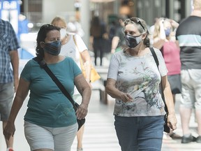 People wear face masks as they walk through a shopping mall in Montreal, Saturday, July 18, 2020, as the COVID-19 pandemic continues in Canada and around the world.