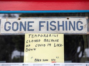 A sign reading "Gone Fishing" is pictured on the window of a closed barber shop in Santa Monica, Calif., Tuesday, July 28, 2020.