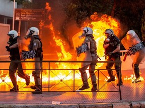 Riot cops try to avoid petrol bombs thrown by protesters outside the Greek Parliament during a demonstration against a new law on protest rules in Athens, on July 9, 2020.