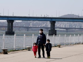 A man and children wearing masks to protect against contracting the coronavirus disease (COVID-19) take a walk at a Han River Park in Seoul, South Korea April 4, 2020.