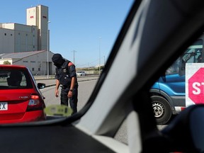 A Police officer checks the documents of people travelling on vehicles at the entrance of Lleida after Catalonia's government imposed new restrictions to control a new coronavirus disease (COVID-19) outbreak in Lleida, Spain, July 4, 2020.