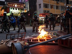 Riot police walk past a fire set by anti-national security law protesters during a march at the anniversary of Hong Kong's handover to China from Britain in Hong Kong, China, Wednesday, July 1, 2020.