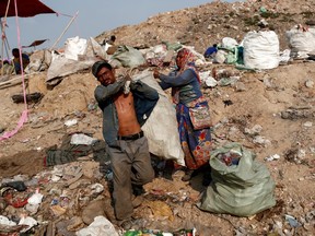 Latifa Bibi, 38, helps her husband Mansoor Khan, 44, a waste collector, carrying a sack of recyclable materials that they found at a landfill site, after finishing work for the day, during the coronavirus disease (COVID-19) outbreak, in New Delhi, India, July 9, 2020.