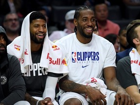 Paul George, left, and Kawhi Leonard of the L.A. Clippers laugh on the bench during a 120-99 win over the Phoenix Suns at Staples Center on Dec. 17, 2019 in Los Angeles, Calif.