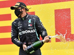 Mercedes' Lewis Hamilton wears a protective face mask as he celebrates winning the race on the podium, following the resumption of F1 after the outbreak of the coronavirus disease (COVID-19).