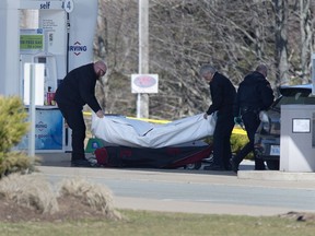 Workers with the medical examiner's office remove a body from a gas bar in Enfield, N.S. on April 19, 2020.