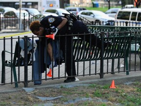 A police officer from the NYPD puts down evidence markers near a crime scene in the Brooklyn borough of New York July 6, 2020.