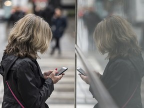 A woman uses her cell phone in Toronto’s Financial District on Tuesday, March 10, 2020.