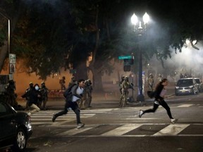 Federal law enforcement officials fire tear gas and other non lethal methods at demonstrators during a protest against racial inequality in Portland, Ore., Sunday, July 19, 2020.