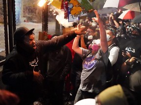 A protester drops a burning box while attempting to throw it over a perimeter fence in front of the Mark O. Hatfield U.S. Courthouse in Portland, Ore., Thursday, July 23, 2020.