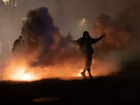 A protester walks through tear gas deployed by federal law enforcement officers during a demonstration against police violence and racial inequality in Portland, Oregon, Tuesday, July 28, 2020.
