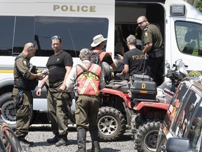 Police officers man a command post, Friday, July 10, 2020 in Saint-Apollinaire, Que. Police are continuing their search around a Quebec City suburb after they issued an Amber Alert Thursday for two young girls and their 44-year-old father who investigators believe disappeared following a highway car crash.