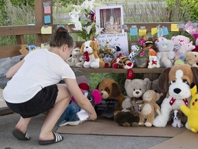 CP-Web.  A teenager leaves a message at a memorial for Norah and Romy Carpentier, Sunday, July 12, 2020 in Levis, Que. The bodies of Norah and Romy Carpentier, aged 11 and 6, were found in a wooded area of a Quebec City suburb on Saturday.