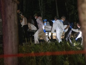 A body believed to be Martin Carpentier is carried by police investigators, Monday, July 20, 2020 in Saint-Apollinaire, Que.
