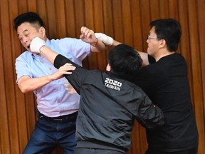 Taiwan's main opposition Kuomintang (KMT) legislator Lu Ming-che (left) fights with ruling Democratic Progressive Party (DPP) lawmaker Wu Ping-jui (middle) as scuffles broke out during voting at the parliament in Taipei on July 17, 2020.