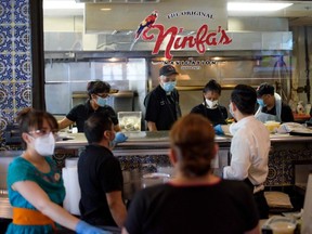 In this file photo taken on May 1, 2020, servers at The Original Ninfa's wear gloves and masks while bringing takeout orders to the kitchen amid the novel coronavirus pandemic in Houston.