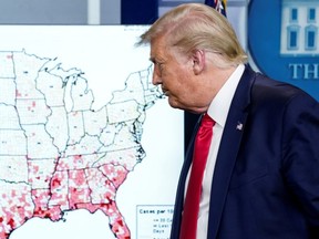 U.S. President Donald Trump walks past a map of reported coronavirus cases as he departs following a news briefing at the White House in Washington July 23, 2020.