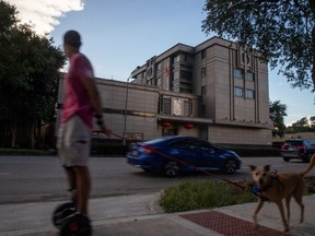 A man on a hoverboard walks his dog past the China Consulate General in Houston, Texas, U.S., July 22, 2020.
