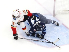 EDMONTON, ALBERTA - AUGUST 04: Josh Morrissey #44 of the Winnipeg Jets knocks Johnny Gaudreau #13 of the Calgary Flames away in the third period in Game Three of the Western Conference Qualification Round prior to the 2020 NHL Stanley Cup Playoffs at Rogers Place on August 04, 2020 in Edmonton, Alberta.